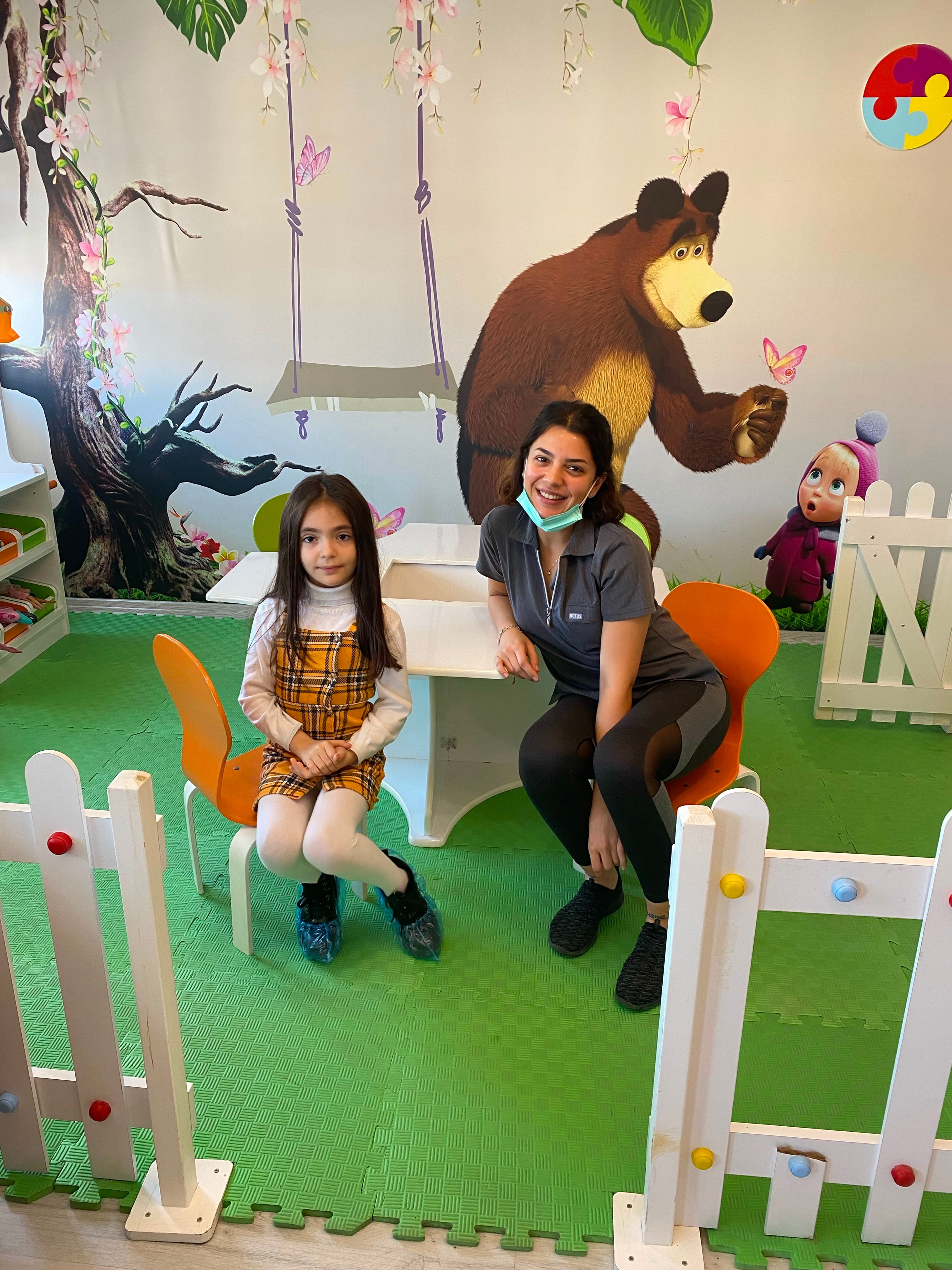 Klinik oyun alanında salıncakta çocuk ve hekim